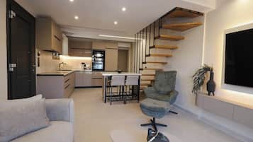 Um interior moderno com cozinha, área de refeições e um espaço de estar com sofá e poltrona.