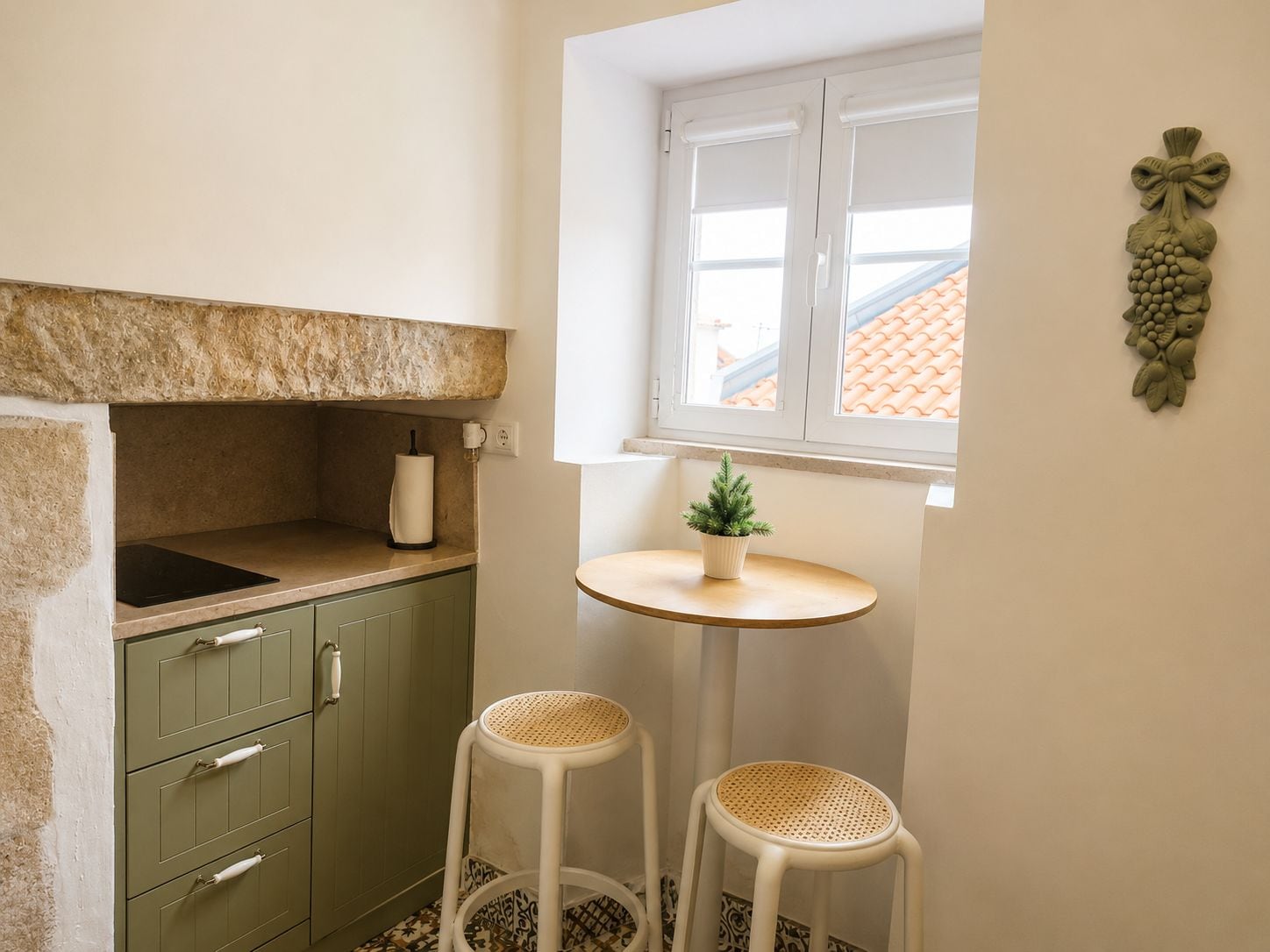Cozinha pequena com bancada de pedra, janela com vista e dois banquinhos.