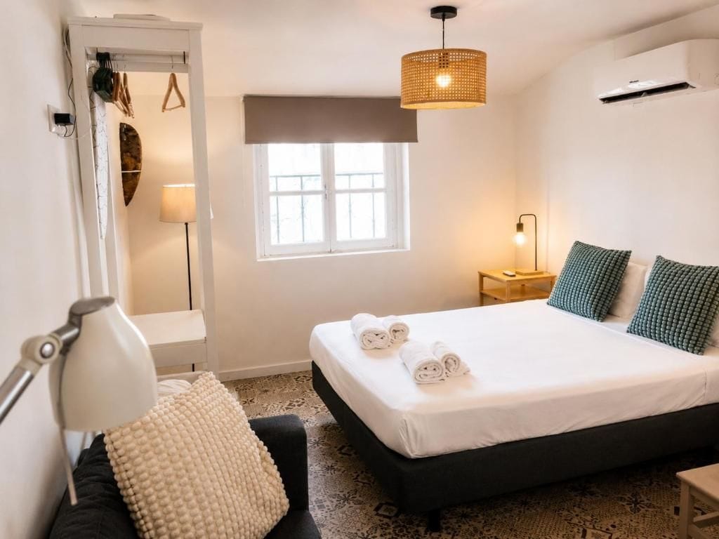 A bedroom with a bed, bedside lamps, a window, and a hanging light fixture.