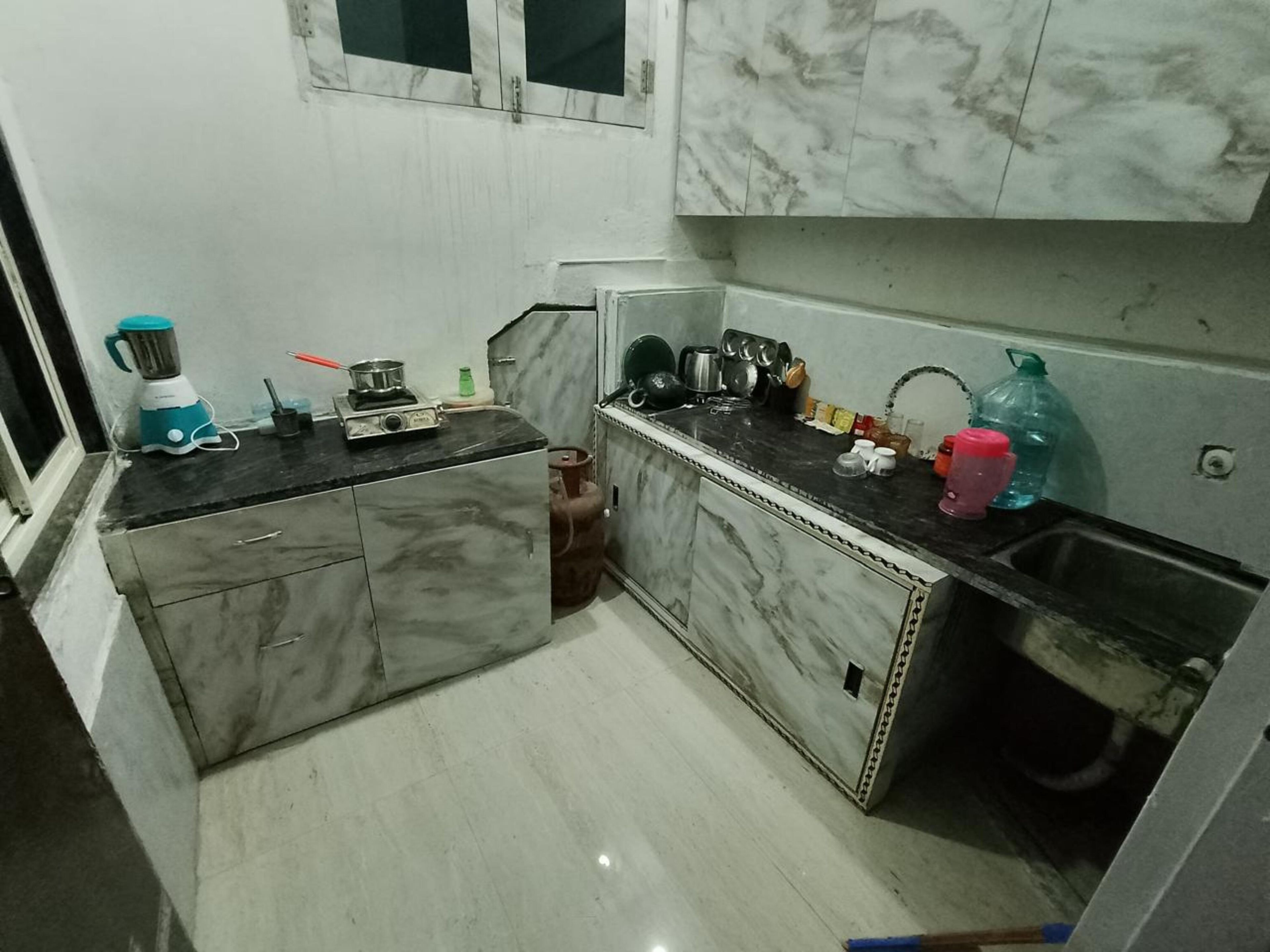 Una cucina compatta con piani in marmo, un fornello a gas e un frullatore.