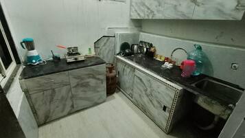 Una cucina compatta con piani in marmo, un fornello a gas e un frullatore.