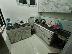 A compact kitchen with marble countertops, a gas stove, and a blender. - Radha Madhav Kutir (Vrindavan)