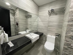 Un bagno moderno con un piano d'appoggio nero, lavandino bianco e water.