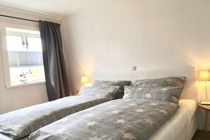 A bedroom with two beds, a window with curtains, and bedside lamps. - 4 "Northern tip" in Letj Reethüs (Norddorf)