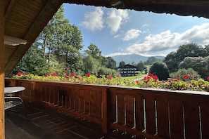Eine Holzterrasse mit Blick auf einen Berg und ein Gebäude in der Ferne.