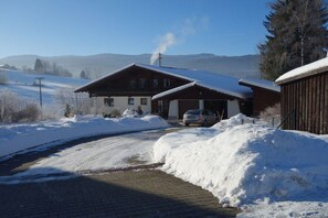 Eine verschneite Landschaft mit einer Holzhütte und einem geparkten Auto davor.