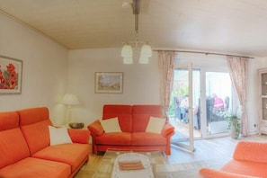A room with two orange sofas, a white table, and a glass door leading outside. - Holiday home with 3 bedrooms (Nordstrand)