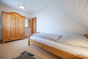Ett sovrum med en säng i trä, en garderob och en spegel.