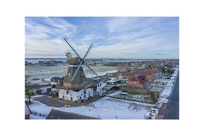 Un moulin à vent situé dans un paysage rural, avec des maisons en arrière-plan.