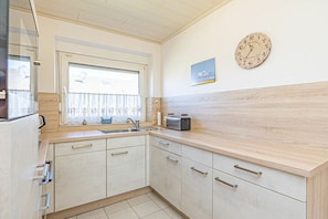 A kitchen with a window, a clock, and a toaster on the counter. - Holiday home with 3 bedrooms (Nordstrand)