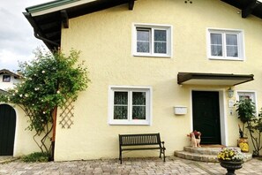A two-story building with a green door, white-framed windows, and a bench outside. - Prestige Apartment Chiemsee (Prien)
