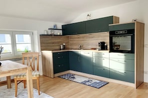 Eine moderne Küche mit dunklen Schränken, einer Holz Arbeitsplatte und einem eingebauten Backofen.