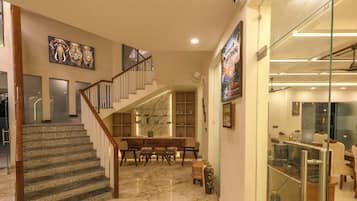 A spacious interior with a marble staircase, a dining area, and a glass-fronted shop.