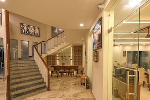 Un interior espacioso con una escalera de mármol, un comedor y una tienda con escaparate de vidrio.