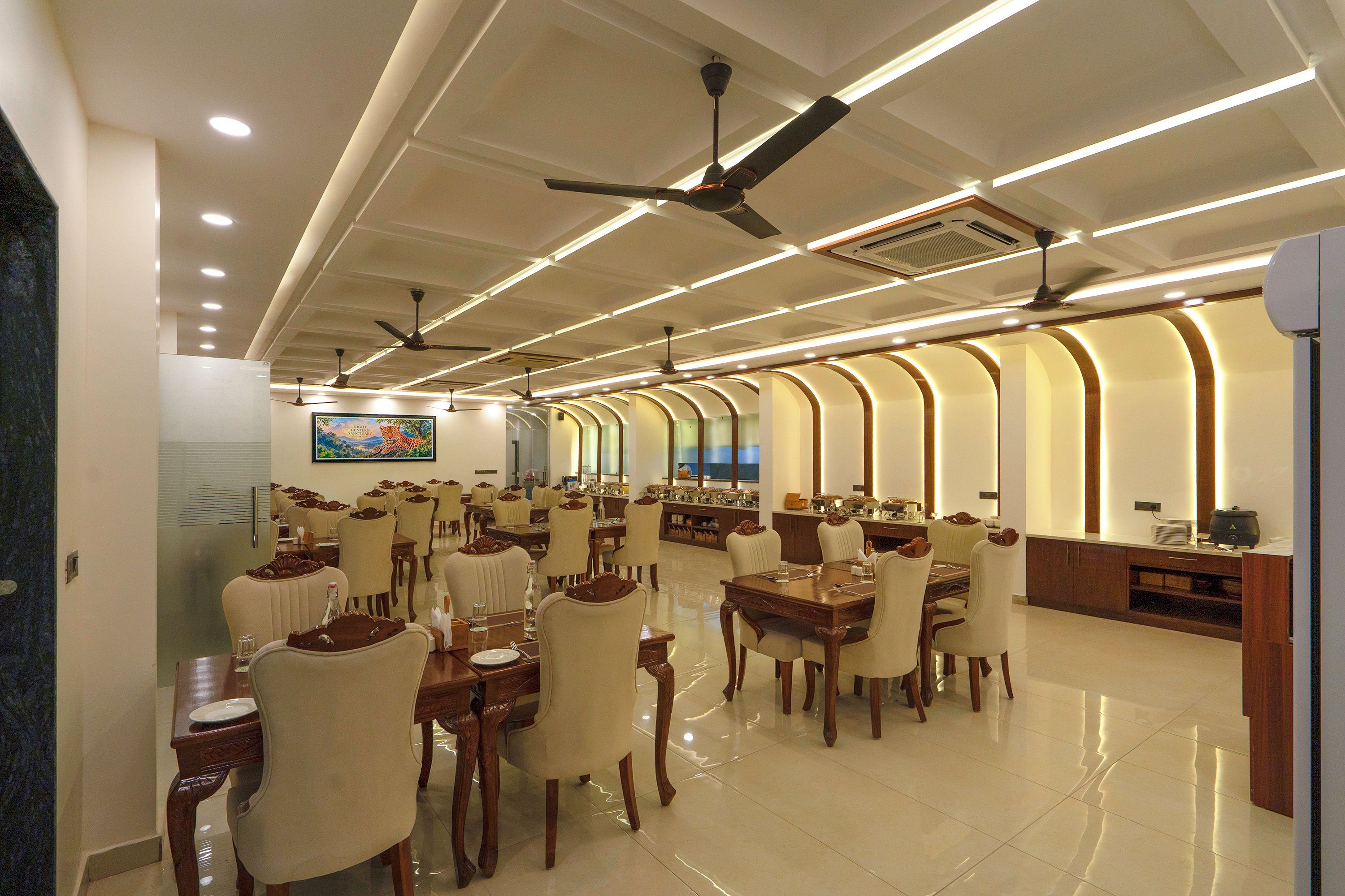 Un vaste espace dédié à la salle à manger, avec de nombreuses tables et chaises, des ventilateurs de plafond et un éclairage encastré.