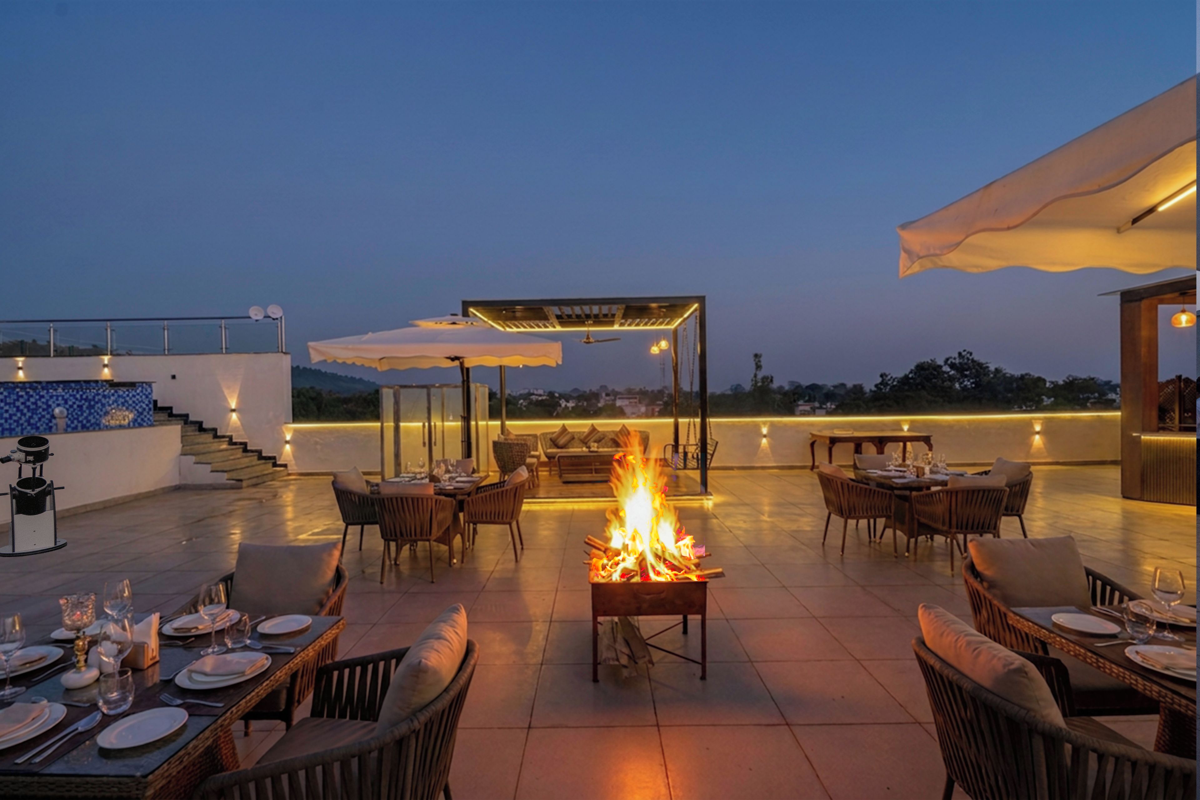 Un espacio de comedor al aire libre con mesas y sillas, una chimenea y una zona de estar cubierta.