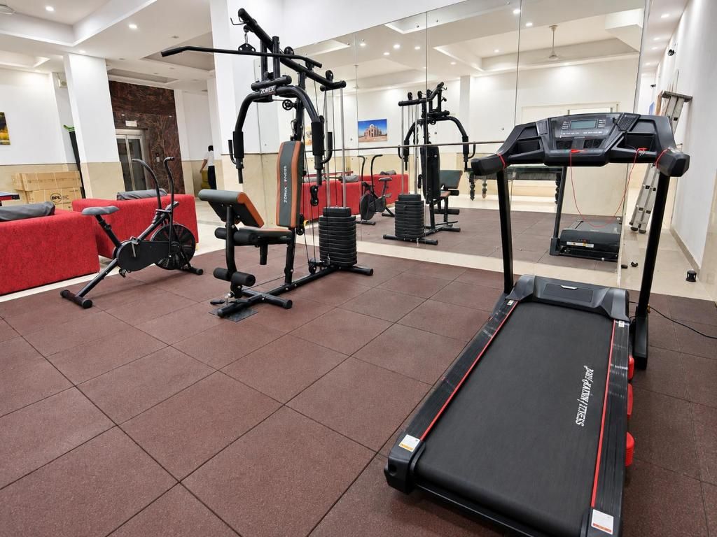 A gym with cardio equipment, weight machines, and a red seating area.