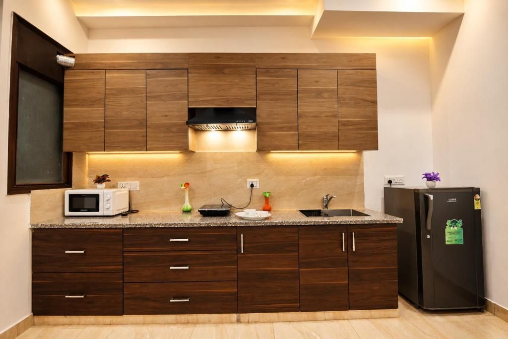 Een moderne keuken met houten kastjes, een magnetron, een spoelbak en een koelkast.