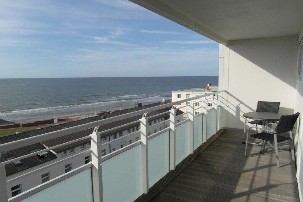 Un balcon avec vue sur l’océan, une table et des chaises.