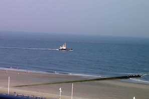 A beach with a boat in the water, a sandy shore, and a clear sky. - House North Sea View 142 (Norderney)
