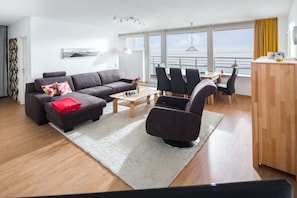 A modern living room with a sofa, chairs, a coffee table, and a view of the sea. - House North Sea View 142 (Norderney)
