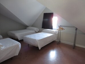 A room with two beds, a radiator, and a window with curtains.