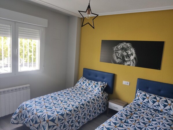 A bedroom with two beds, a star-shaped light fixture, and a large animal print on the wall.