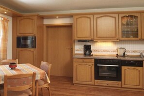 A kitchen with wooden cabinets, a microwave, a coffee maker, and a dishwasher. - Holiday home in Neuhaus with swimming pool (Neuhaus)
