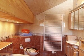 A bathroom with a wooden ceiling, a white radiator, a sink, and a toilet. - Holiday home in Neuhaus with swimming pool (Neuhaus)