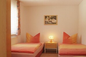 A bedroom with two beds, a nightstand with a lamp, and a painting on the wall. - Holiday home in Neuhaus with swimming pool (Neuhaus)