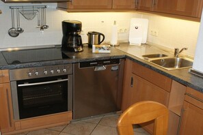 A compact kitchen with a dishwasher, oven, coffee maker, and a sink. - Holiday apartment with 2 bedrooms (Heringsdorf)