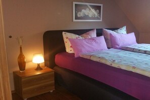 A bedroom with a bed, nightstand, lamp, and a framed picture on the wall. - Holiday apartment with 3 bedrooms (Karlshagen)
