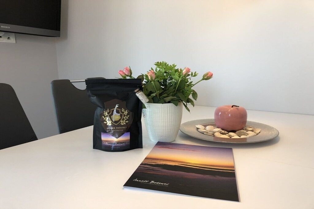 A table with a bag of chocolate, a potted plant, a candle, and a book.