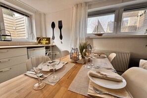 A dining area with a wooden table set for two, a coffee sign, and a view of the outside. - Kühlungsborn - SeaSide No. 6 (Kuehlungsborn)