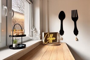 A modern interior with a wooden table, a neon coffee sign, and wall-mounted cutlery. - Kühlungsborn - SeaSide No. 6 (Kuehlungsborn)
