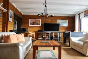 Ein Wohnzimmer mit einer Couch, einem Couchtisch, einem Fernseher und einem Billardtisch.