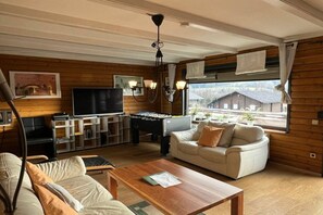 Ein gemütliches Wohnzimmer mit Sofa, Couchtisch, Fernseher und einem Kicker.