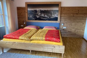 A bed with a wooden frame and a large painting of a mountain landscape above it. - Holiday apartment with 1 bedroom (Bischofswiesen)