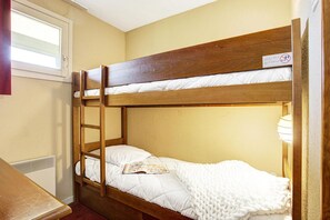 A bunk bed with a ladder, a window, and a table with a book. - 100m from ski slopes, parking, ski locker, 35m², Pyrénées 2000 (Pyrénées 2000)