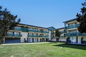 A multi-story building with balconies, a grassy courtyard, and a clear blue sky. - 100m from ski slopes, parking, ski locker, 35m², Pyrénées 2000 (Pyrénées 2000)