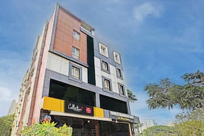 A multi-story hotel with a modern facade, featuring a prominent signage for 'Sheesham Home The Wood Studio' and 'Collection Hotel SSR Royal Suites'. - Collection O SSR Royal Suites (Hyderabad)