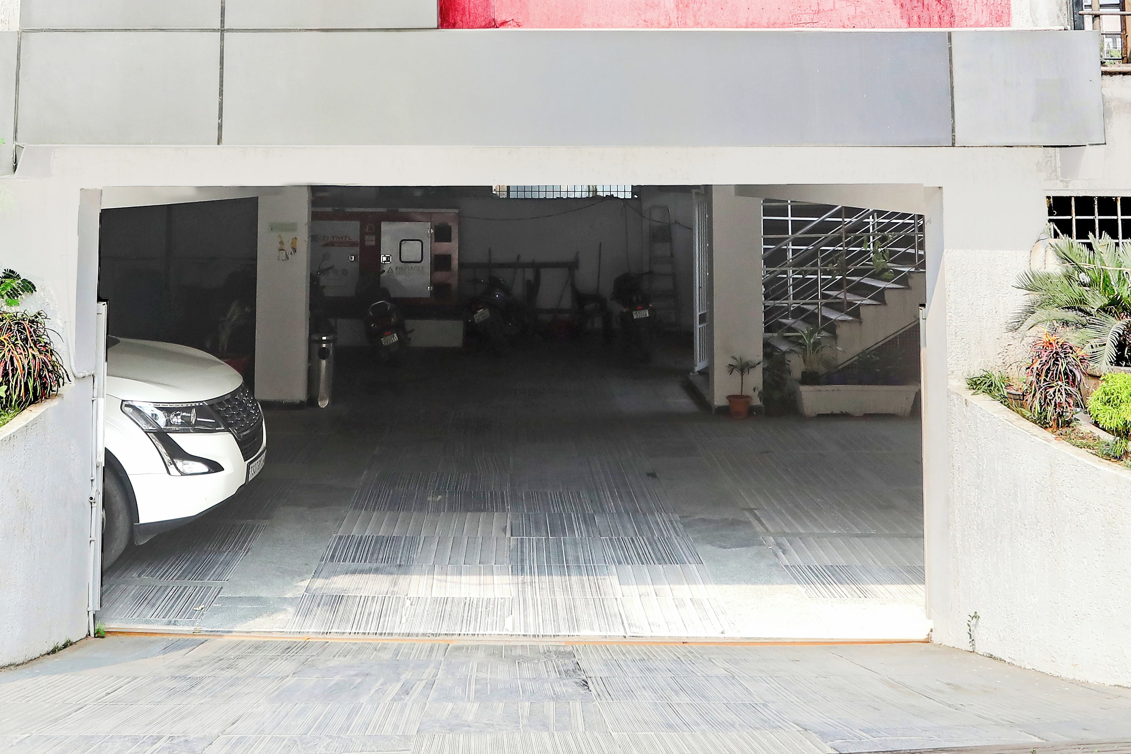 Entrada de um estacionamento com um carro branco estacionado dentro.