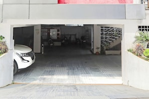 Entrada de um estacionamento com um carro branco estacionado dentro.