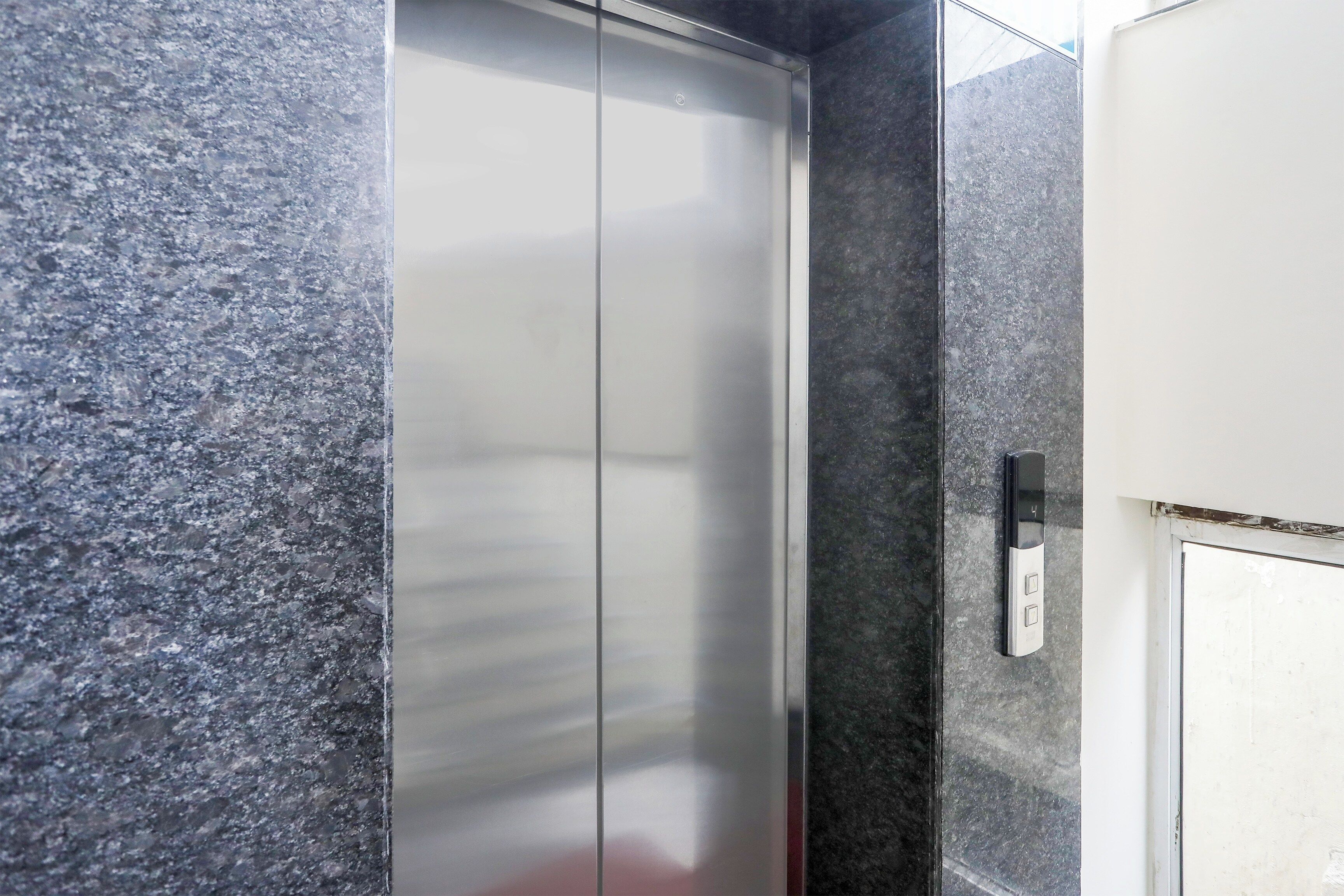 A metallic elevator door with a control panel on the wall beside it.
