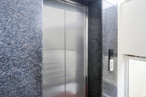 A metallic elevator door with a control panel on the wall beside it. - Collection O SSR Royal Suites (Hyderabad)