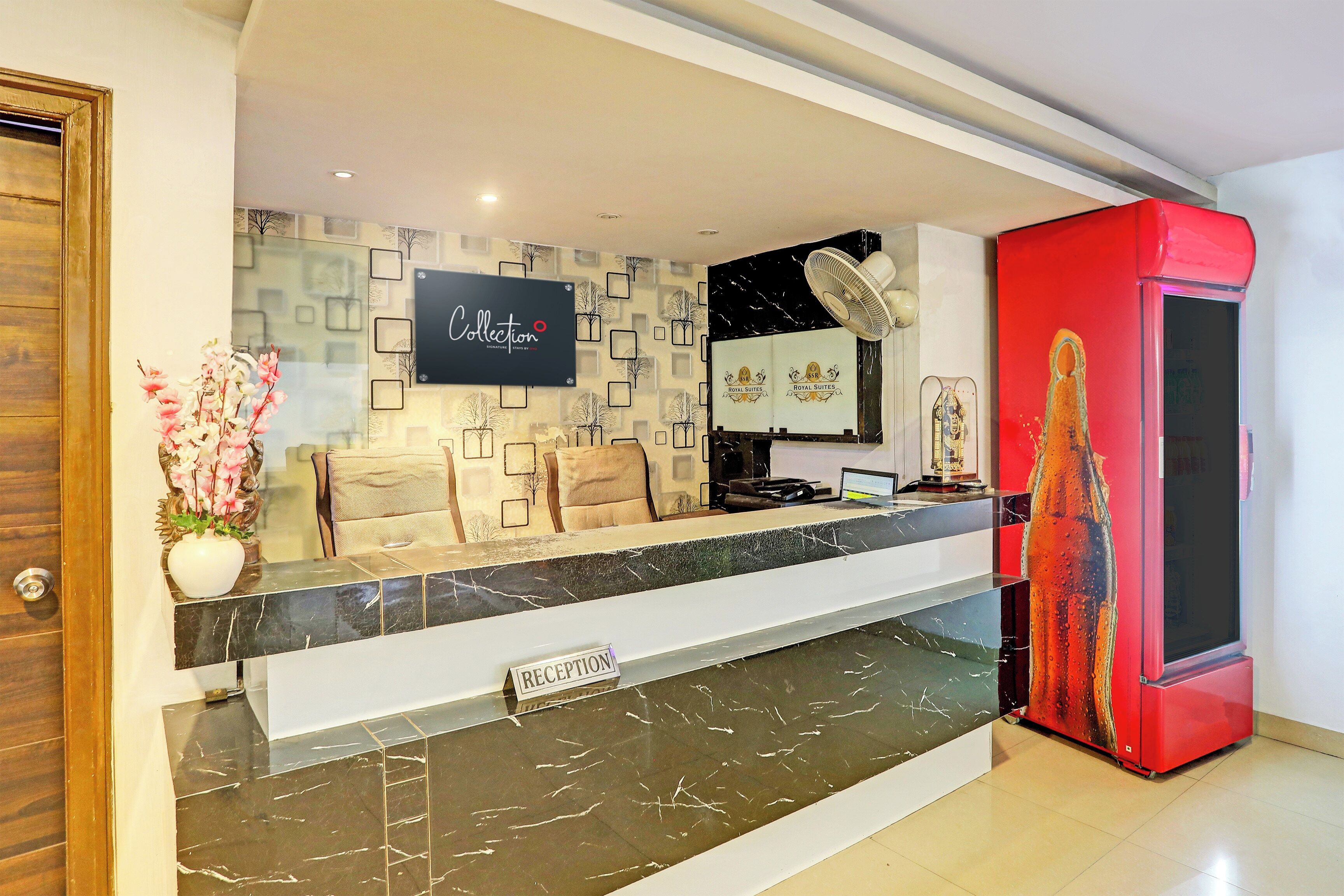 A reception area with a marble counter, a sign reading 'Collection Signature Stays by King', and a red cabinet to the right.