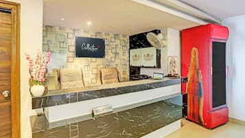 A reception area with a marble counter, a sign reading 'Collection Signature Stays by King', and a red cabinet to the right.