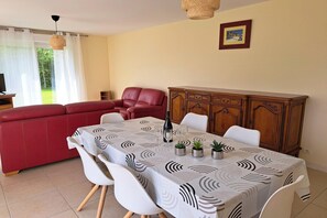 A dining area with a table set for four, a red sofa, and a wooden cabinet. - Holiday home in Hanvec for 5 people (Hanvec)