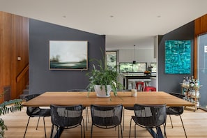 A modern dining area with a wooden table, black chairs, and a potted plant. - Cedar | Treetop Estate with Solar Heated Pool (Mount Eliza)