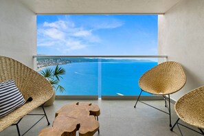 A balcony with wicker furniture, a wooden coffee table, and a view of the sea. - Harbor N2301 by Moikkarentals (Puerto Vallarta)